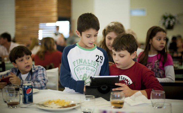 Amigos brincam com tablet no restaurante; no ano passado, nos Estados Unidos, 44% das crianças diziam querer um tablet no Natal. Foto: Isadora Brant / Folhapress