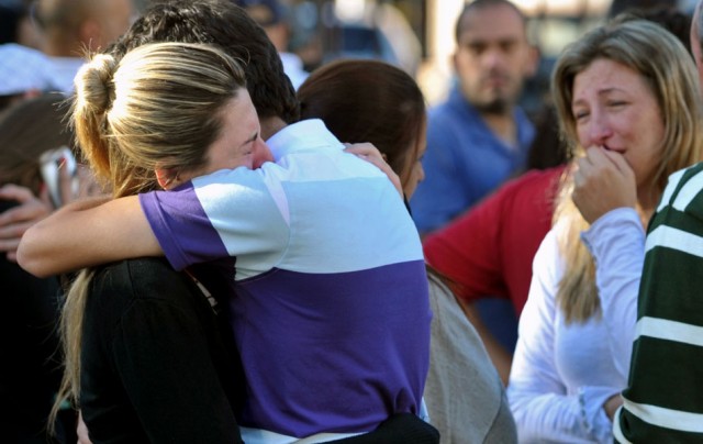 Familiares de vítimas se abraçam em frente a boate Kiss, em Santa Maria. Foto: AP