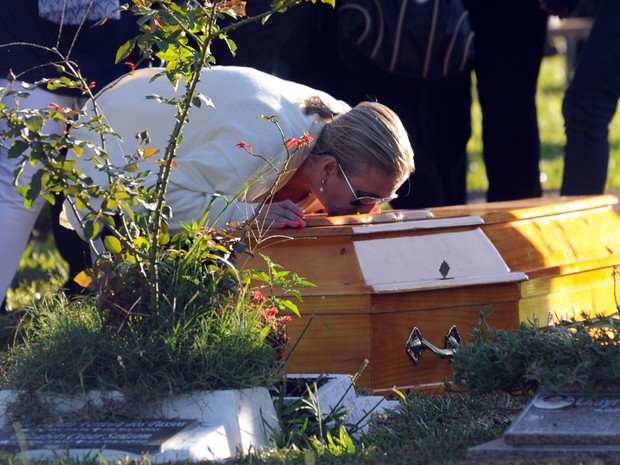 Livia Oliveira, mãe de Heitor, se ajoelha para beijar o caixão do filho durante enterro. Foto: Antonio Scorza/AFP